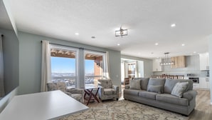 A spacious living area with a grey sofa, a white table, and a patterned rug. - 1 bedroom and kitchen place with a valley scenery view & free parking (CALGARY)