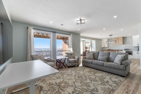 A spacious living area with a grey sofa, a white table, and a patterned rug.