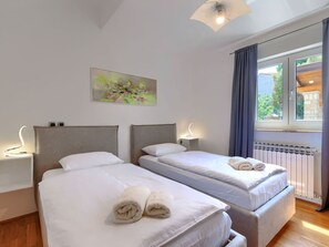 Two single beds with headboards and bedside tables, each with a wall-mounted light, offer a comfortable resting space.