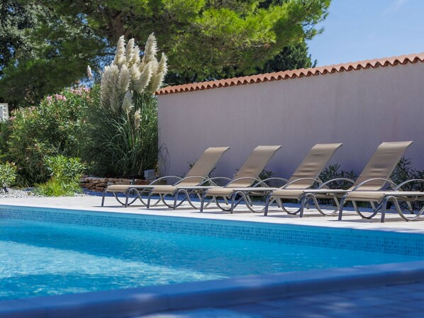 Relax by the tranquil pool surrounded by lush greenery and comfortable sun loungers.