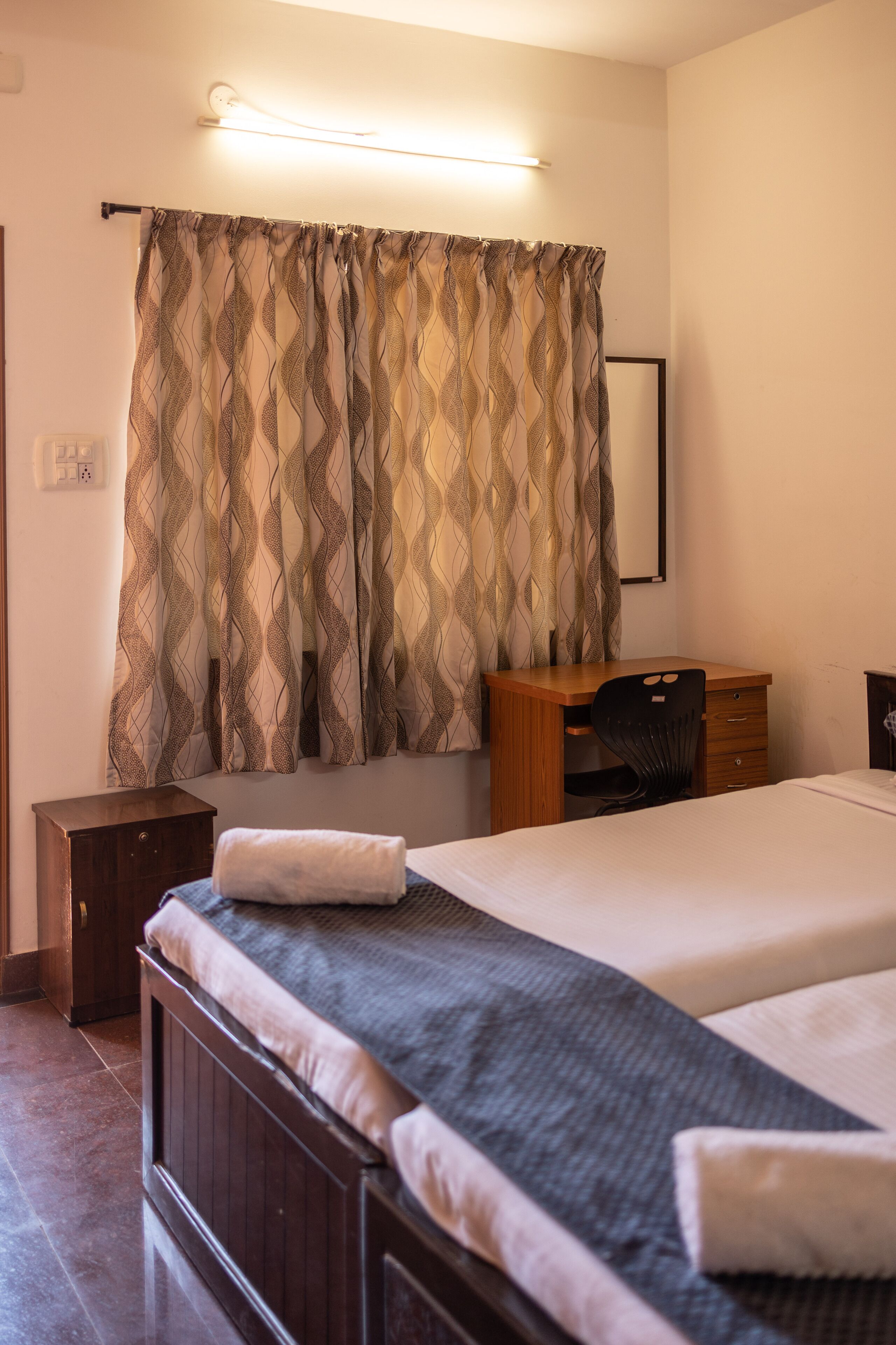 A bedroom with a bed, a desk, and a chair.