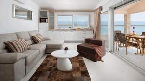 Un salon moderne avec un canapé, une table basse et un coin repas offrant une vue sur la mer.