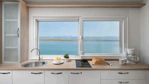 Une cuisine moderne dotée d’une grande fenêtre donnant sur un lac et des montagnes.