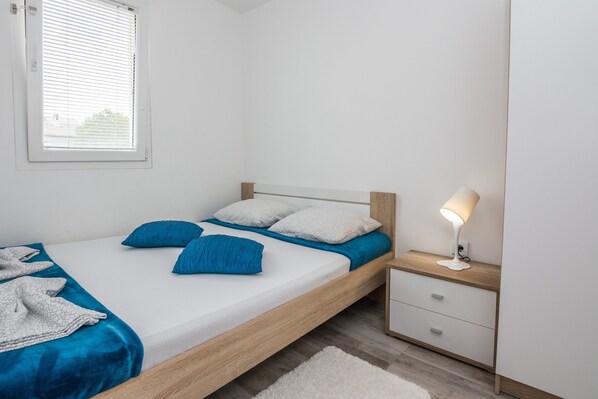 A bedroom with a bed, a nightstand, a lamp, and a window.