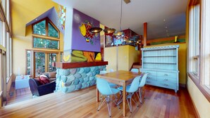 A modern kitchen with a stone wall, wooden table, and blue chairs. - Stunning 3 Bedroom / 3.5 Bathroom Blueberry house with breathtaking Mountain Views (Whistler)