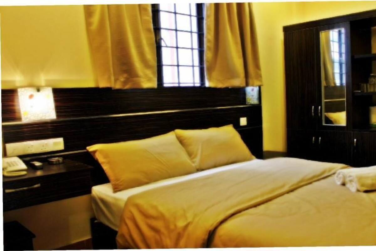 A hotel room with a bed, a nightstand with a phone, a mirror, and a wardrobe.