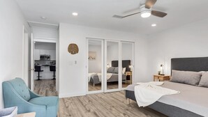 Un dormitorio moderno con una cama grande, un ventilador de techo y vistas a la cocina.