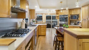 A modern kitchen with wooden cabinets, stainless steel appliances, and a central island with stools. - Waterfront Home w/ Mt Rainier Views, Private Beach, 4 Decks, Sleeps 9 (Bremerton)
