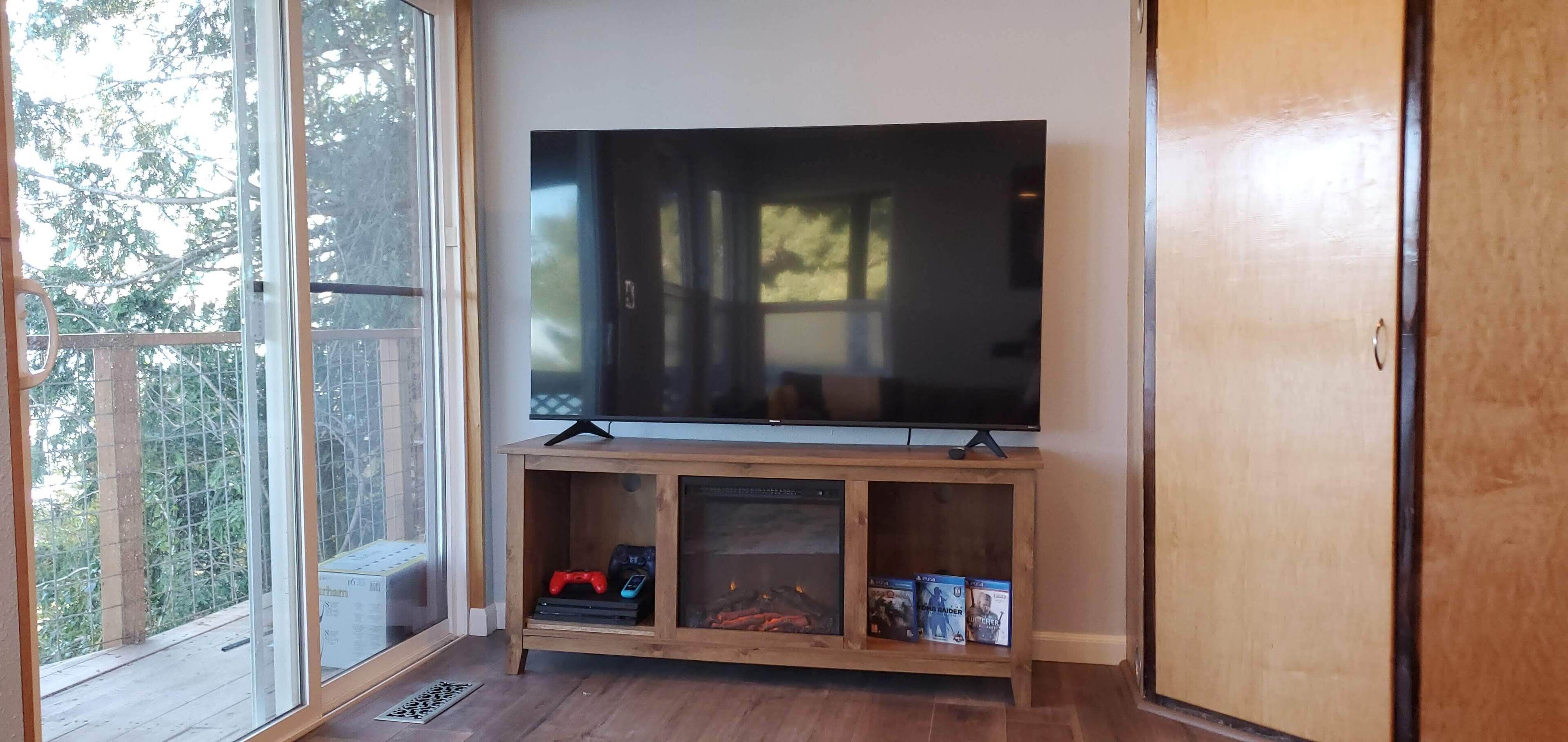Un televisor de pantalla plana sobre un soporte de madera con consolas de videojuegos y juegos de video.