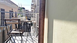 Un balcó amb taula i cadires, una planta en test i una barana.
