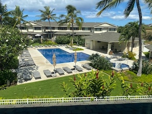 A hotel with a swimming pool, sun loungers, and palm trees.