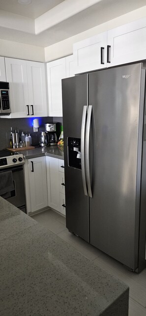 A modern kitchen with stainless steel appliances, white cabinetry, and a built-in oven.