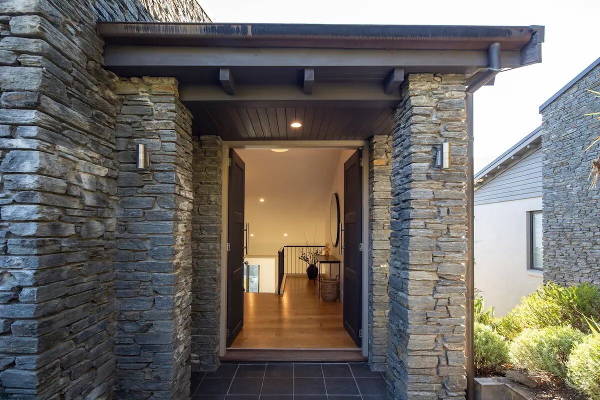 Un bâtiment revêtu de pierres, doté d’une entrée couverte qui mène à un intérieur en bois.
