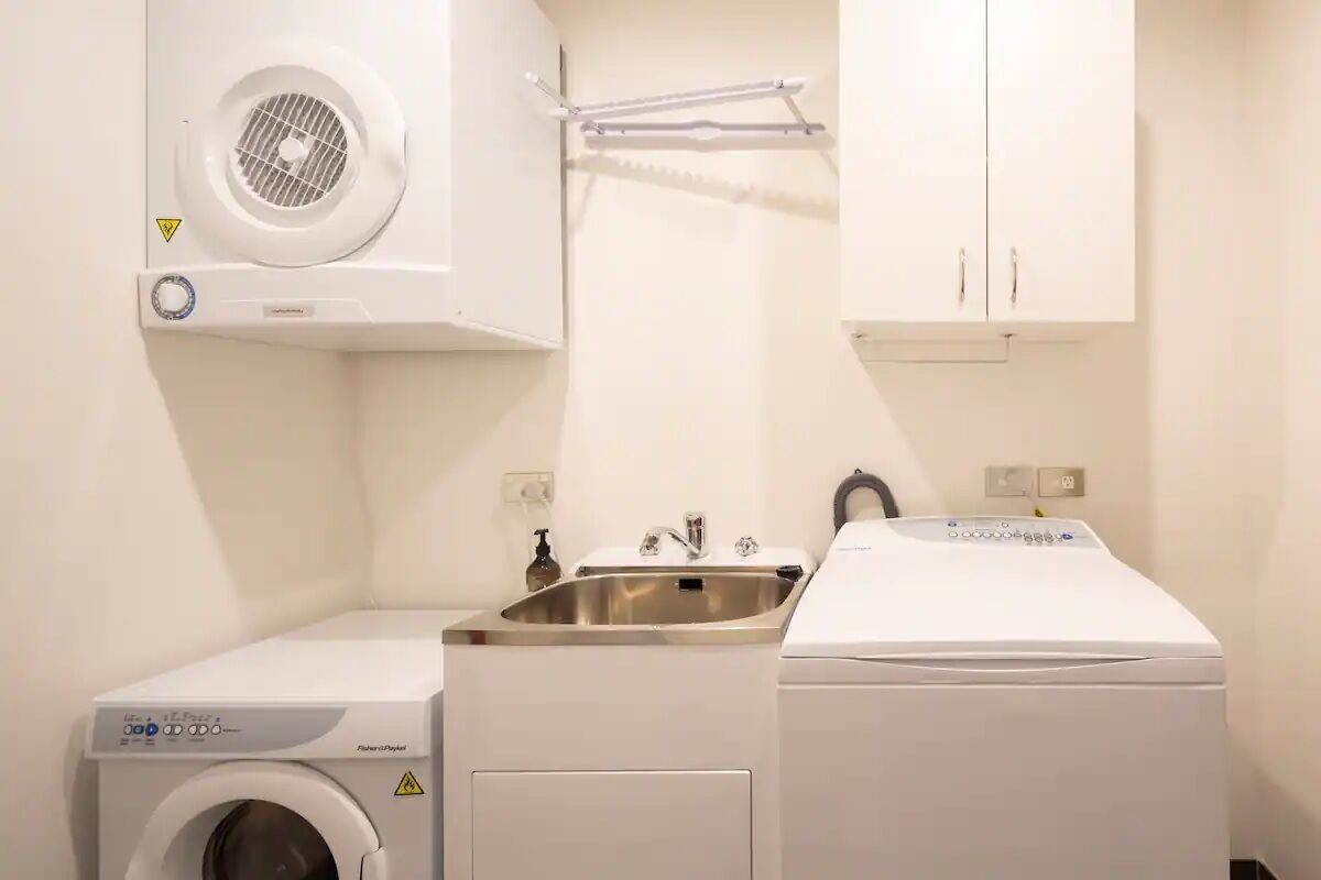 Een wasruimte met een wasmachine, een droger en een wasbak.