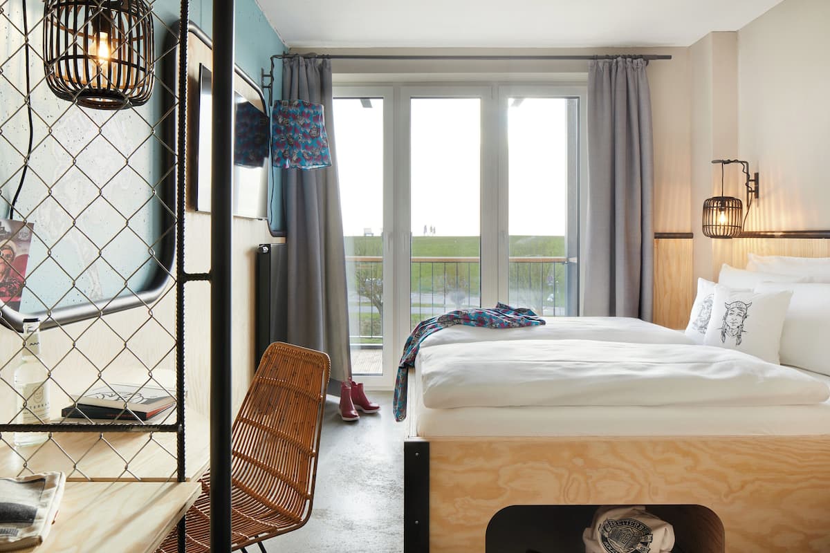 Una habitación de hotel con una cama, una silla, una mesa y vistas al exterior.