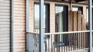 A balcony with a metal railing, wooden slats, and a view of the interior. - Bretterbude Büsum (Büsum)