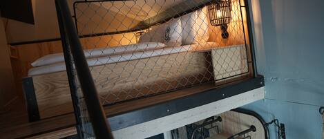 A bunk bed with a metal safety rail and a small enclosed area with a light fixture.