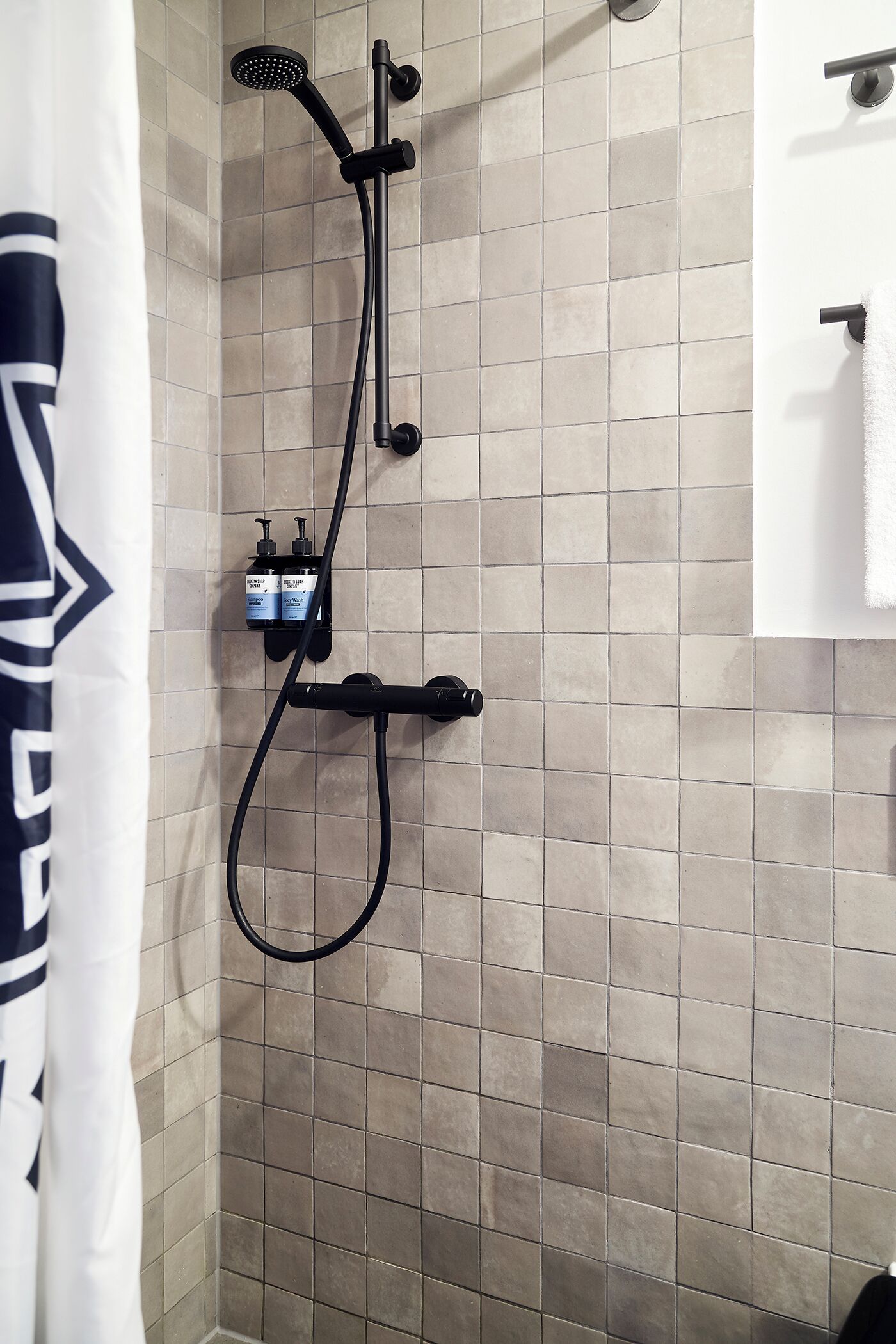 A shower with a handheld showerhead and a wall-mounted control panel.