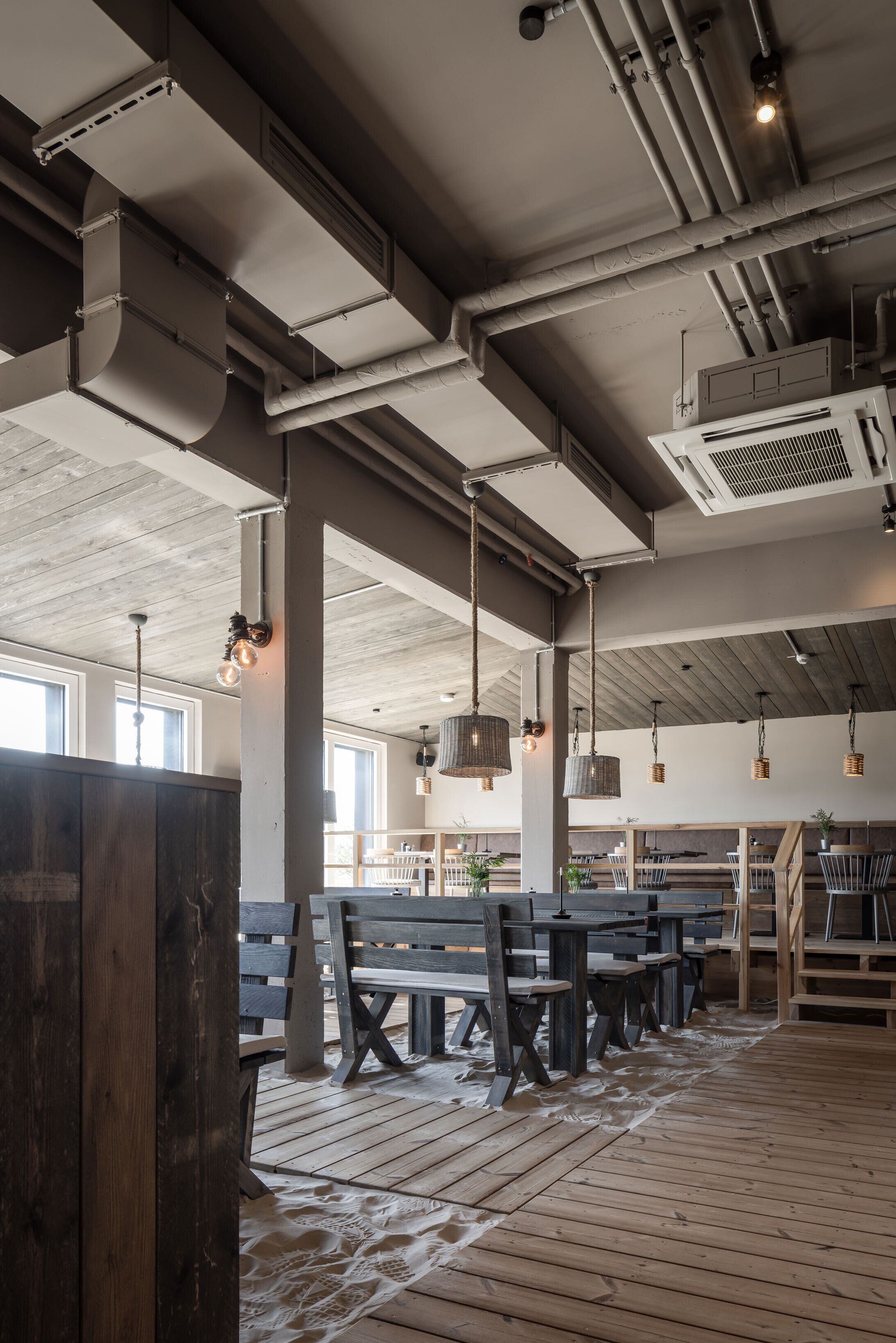 A spacious interior with high ceilings, exposed ductwork, and wooden flooring.
