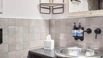 Baño con lavamanos, toallero y estantes.