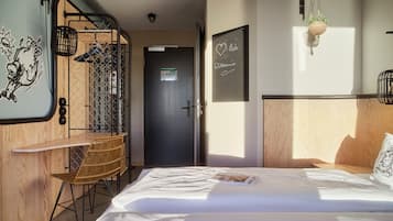 Una camera d'albergo con un letto, una scrivania con una sedia, un armadio e una porta.