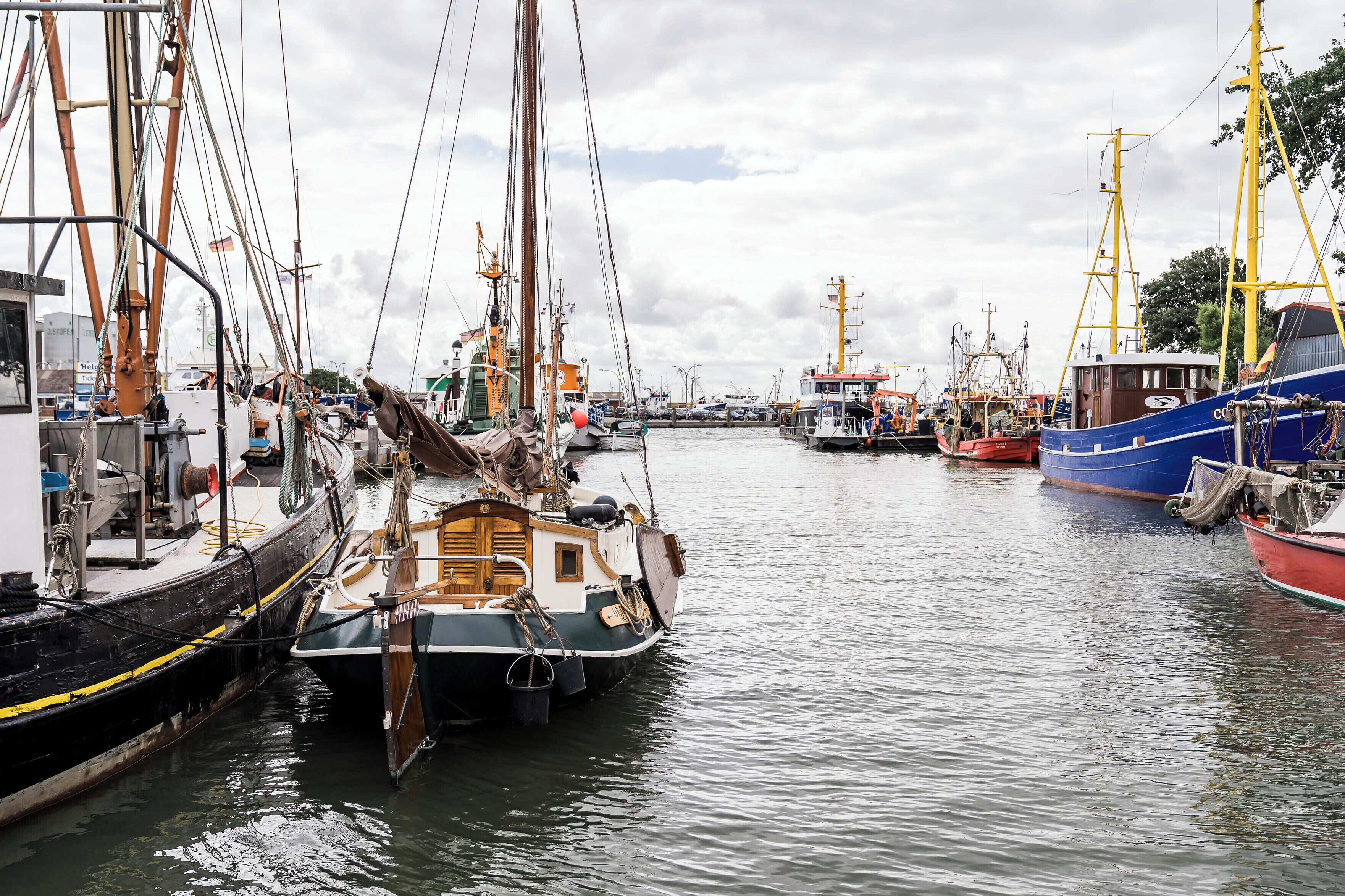 A harbor with multiple boats docked, including a prominent blue and red ship on the right.