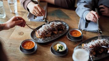 A wooden table with plates of food, bowls of sauces, and glasses of water.
