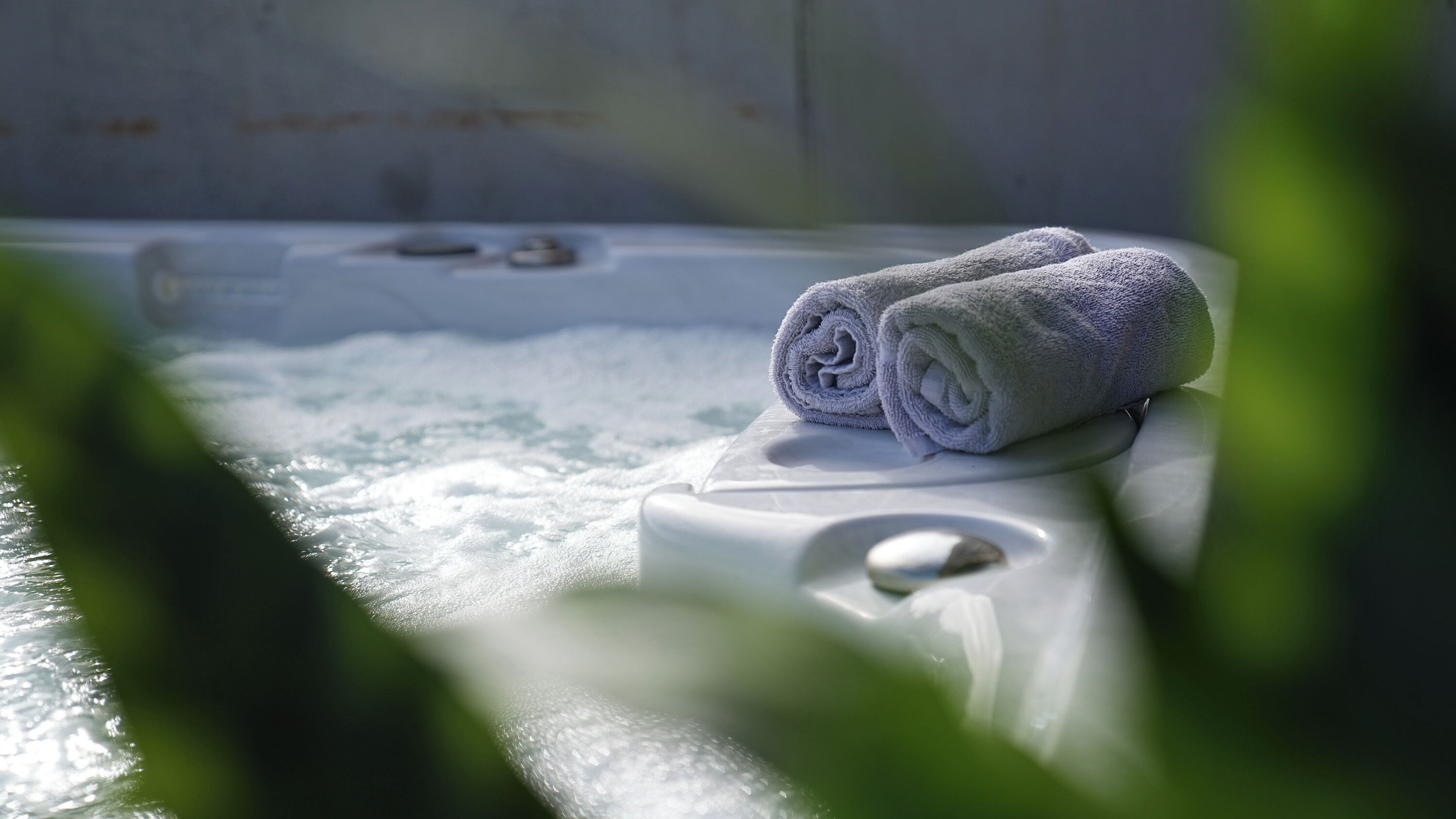 A spa tub with two rolled towels on top, surrounded by water.