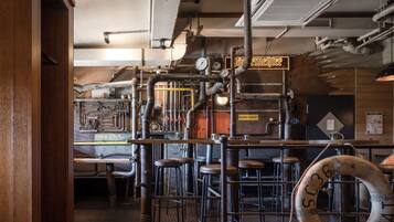 A bar area with stools, a bar counter, and a neon sign.