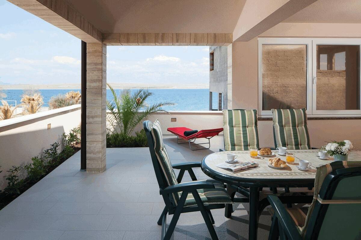 A dining area with a table set for breakfast, overlooking a coastal view.