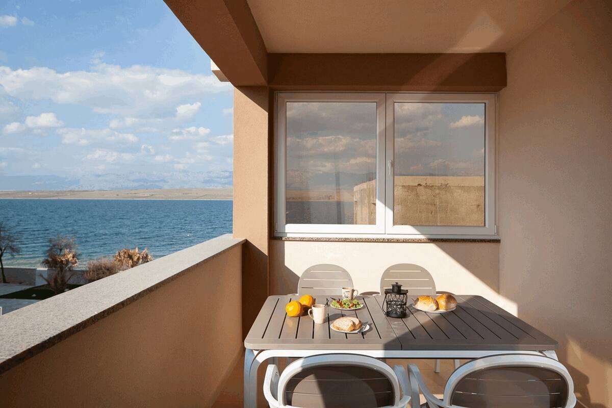 A balcony with a table set for two, overlooking a body of water.