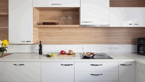 Una cocina moderna con armarios blancos, una encimera de madera y un horno empotrado.