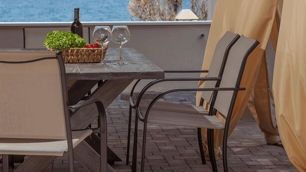 Un patio al aire libre con una mesa y sillas, un cesto de follaje y una botella.