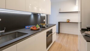 Eine moderne Küche mit weißen Schränken, einer schwarzen Arbeitsplatte und Holzboden.