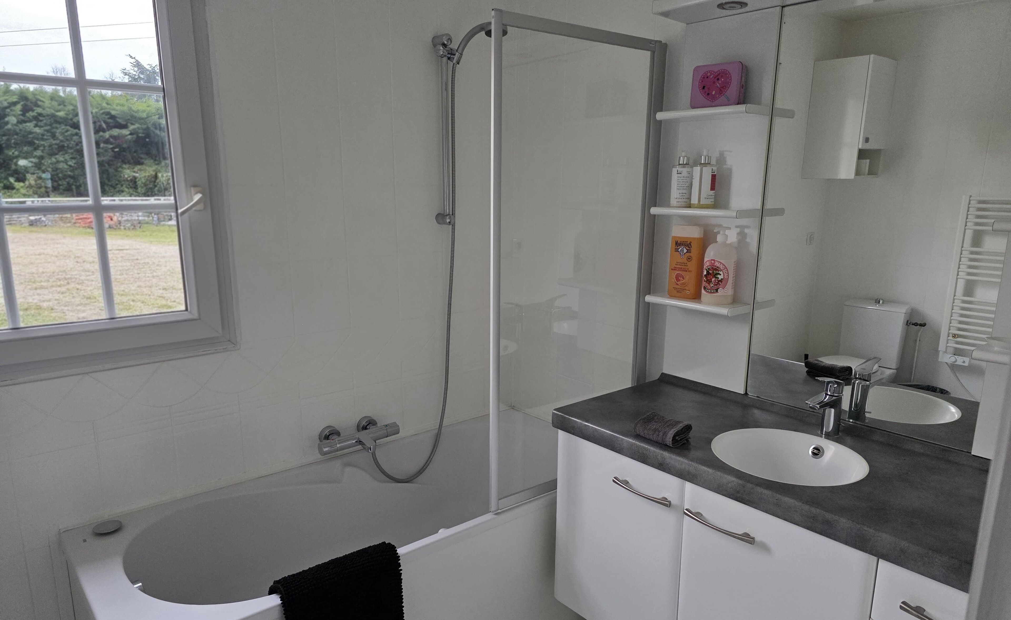 A modern bathroom with a bathtub, a shower, a sink, and a vanity with shelves.