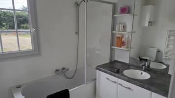 A modern bathroom with a bathtub, a shower, a sink, and a vanity with shelves.