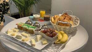 A breakfast buffet with cheese, fruits, bread, and beverages on a white table. - Casabina (Chelles)