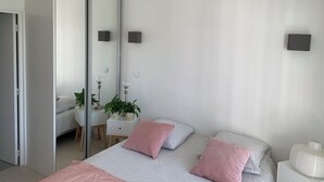 A modern bedroom with a bed, bedside tables, a mirror, and a wardrobe. - Casabina (Chelles)