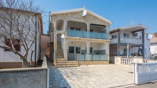 A two-story building with a stone facade, a balcony with glass railings, and a satellite dish on the roof. - Apartment Wenig (Vir)