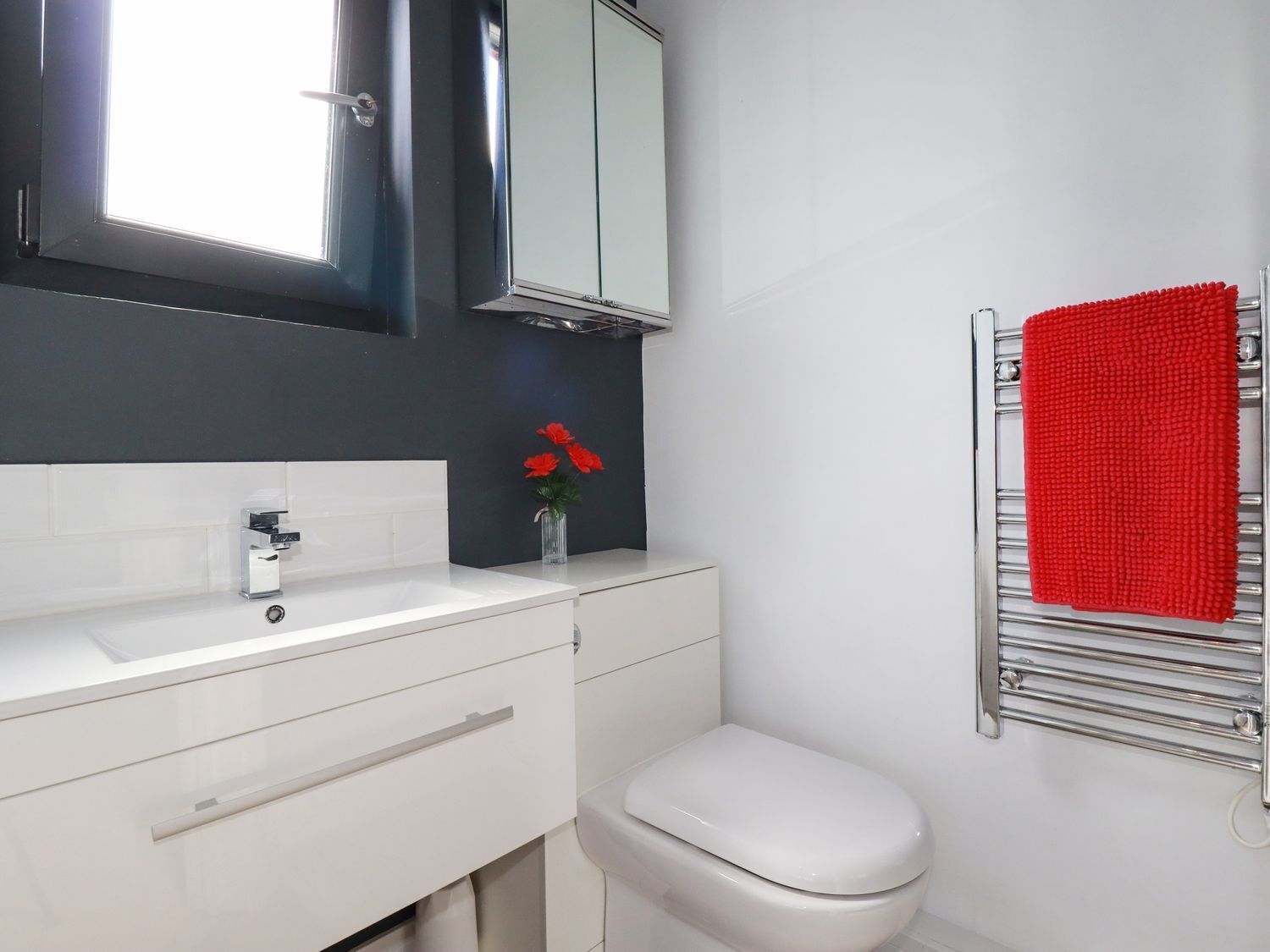 A modern bathroom with a white sink, mirror, and toilet.