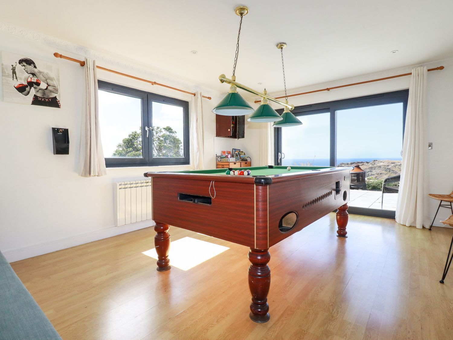 Una mesa de billar en una habitación con ventanas amplias, un radiador y vistas al paisaje.