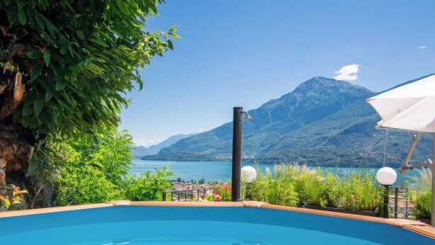 Ein Schwimmbad mit Blick auf eine Berglandschaft, umgeben von viel Grün und blauem Himmel.