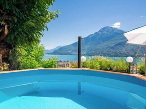Une piscine avec vue sur les montagnes, entourée de verdure et sous un ciel dégagé.