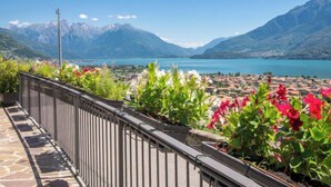 Ein Balkon mit Blick auf einen See, Berge und eine darunterliegende Stadt.