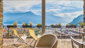 Ein Balkon mit Blick auf einen Berg und einen See, mit zwei Stühlen und einem Tisch.