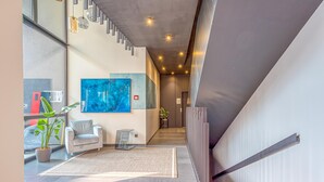 A modern interior with a staircase, a sofa, a rug, and a painting.