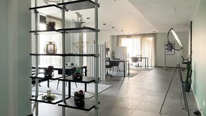 A modern interior with a multi-tiered metal shelving unit, a dining area with a table and chairs, and a workspace with a desk and chair.