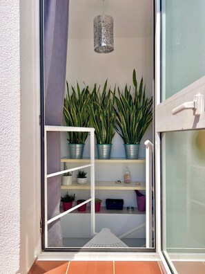 Un balcon agrémenté de plantes en pot, une balustrade blanche et un luminaire suspendu.
