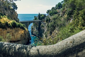 Eine Steinbrücke über einer schmalen Schlucht, darunter ein Boot im Wasser.