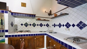 A kitchen with white and blue tiles, wooden cabinets, a gas stove, and a sink.